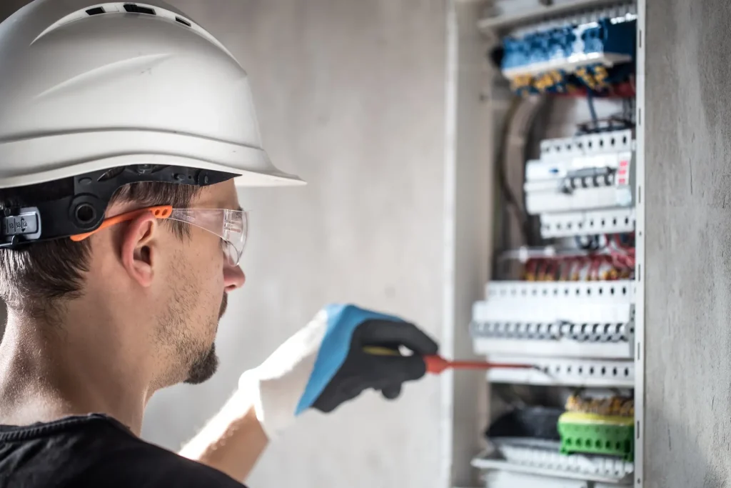 Electricista con casco revisando un cuadro eléctrico